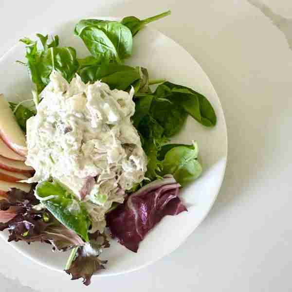 Flat lay of apple chicken salad on a bed of lettuce with a fan of fresh apple slices.